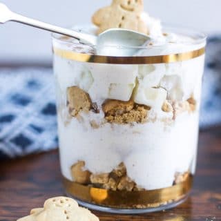 A glass of no bake layered dessert: Pear Gingerbread Parfaits - layers of crushed gingerbread men, gingerbread spiced yogurt and chopped pear.