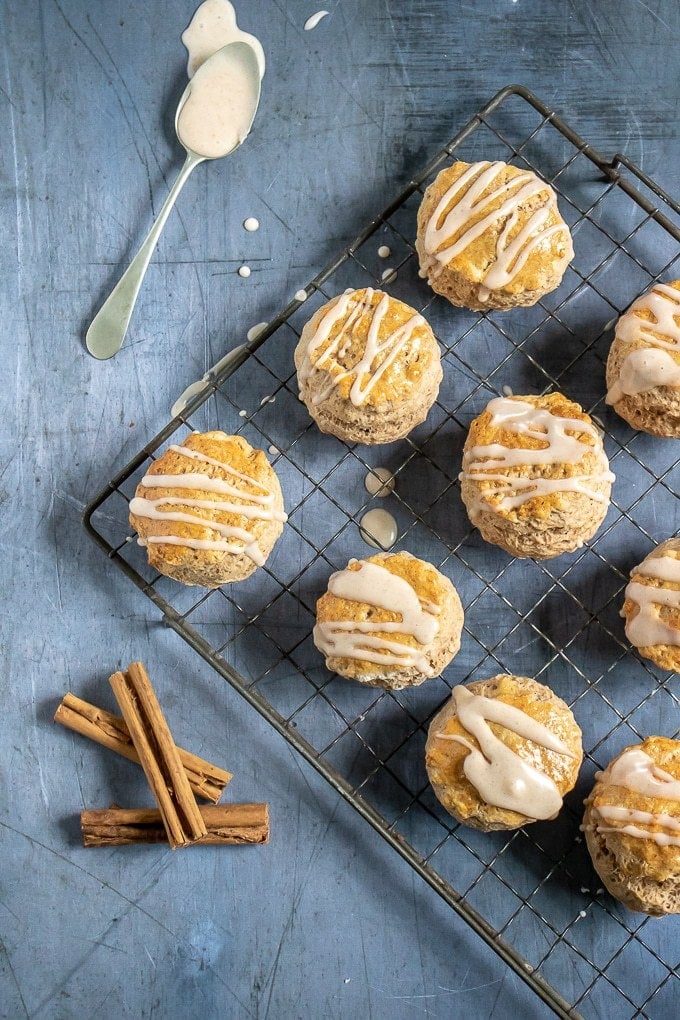 A vintage rack with cinnamon scones with vanilla cinnamon drizzle, next to a spoon and cinnamon sticks. Get the recipe. 