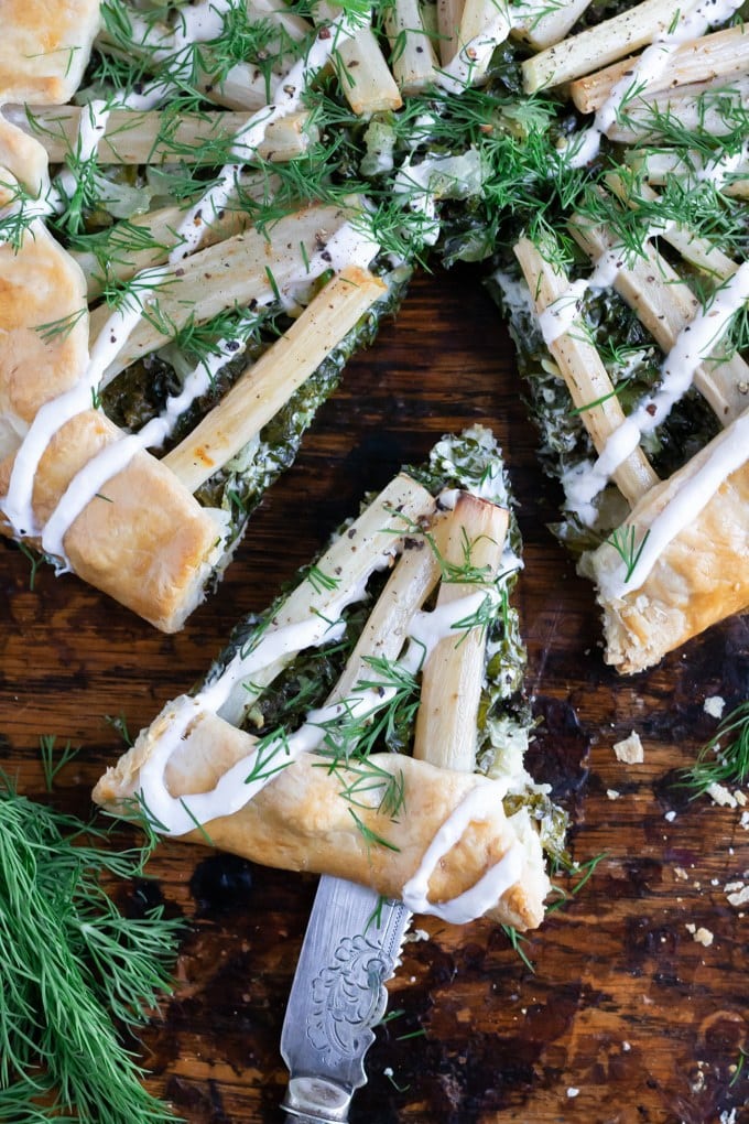 Close up of salsify kale galette with horseradish cream drizzle with a slice taken out.