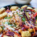 Close up of a bowl of noodle salad with tofu.
