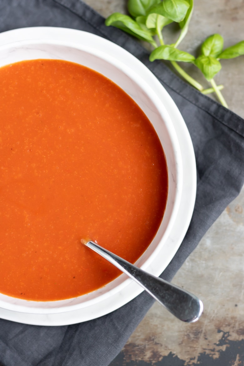 Bowl of homemade creamy tomato soup from scratch on a dark napkin