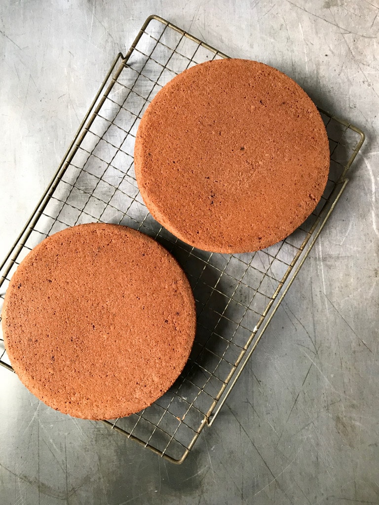 Two chocolate cakes on a cooling rack.