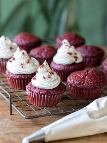 A rack of vegan crimson velvet cupcakes with vegan cream cheese frosting and a piping rating of frosting. Earn the easy one bowl recipe.  Apple Parsnip Cupcakes with Boozy Apple Ci Vegan Red Velvet Cupcakes 4 360x480