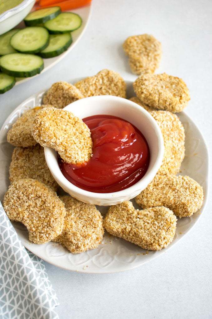 A plate of chickpea nuggets with a bowl of ketchup. 