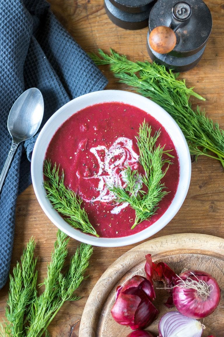 A bowl of smooth beet soup topped with yogurt (or vegan yogurt) and fresh dill. 