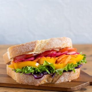 A sandwich sitting on top of a wooden cutting board.