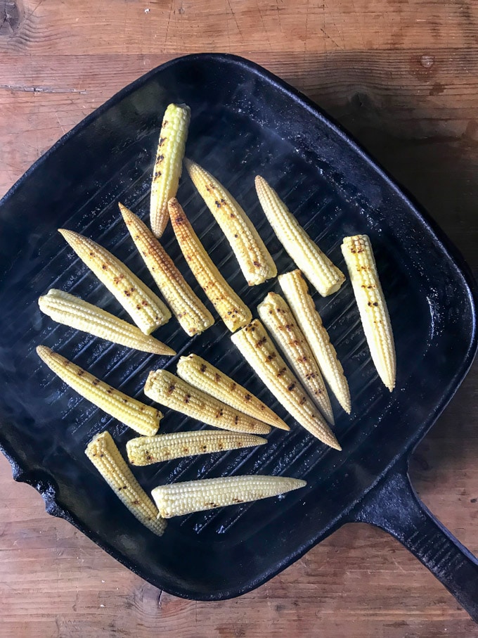 Baby corn on a grill pan cooking to make Mexican street corn (mini appetizer)