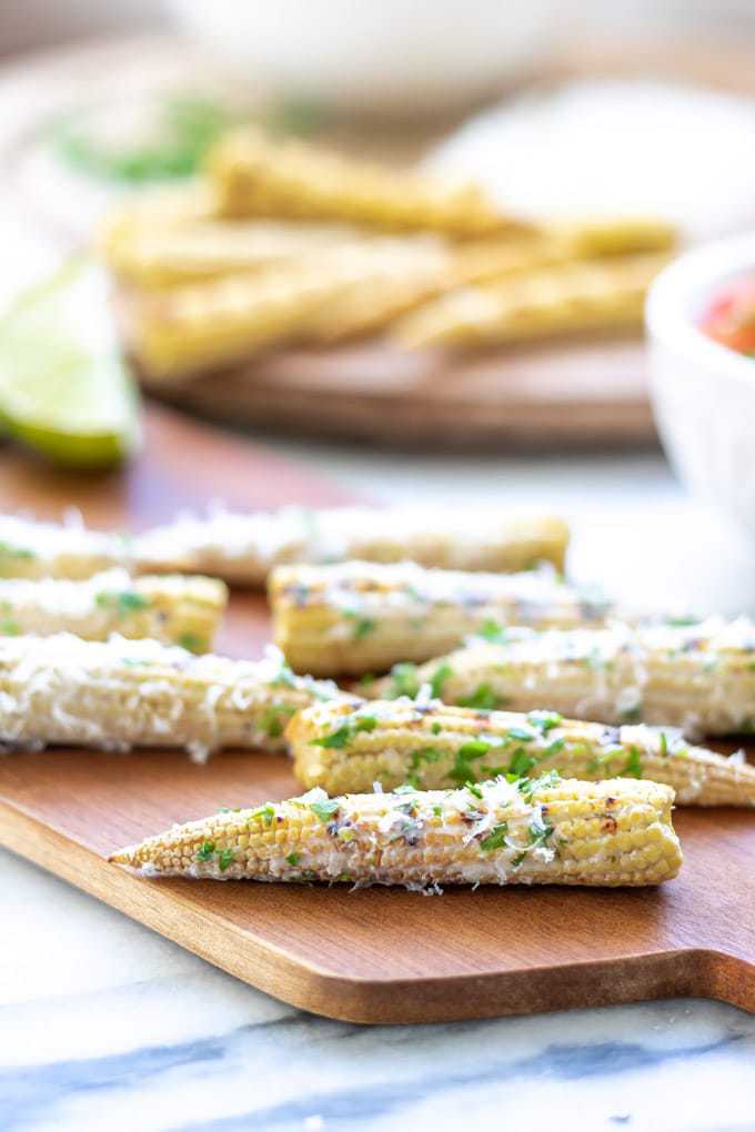 Close up of a mini elote Mexican Street corn made with baby corn. Shown sprinkled with parmesan and herbs.