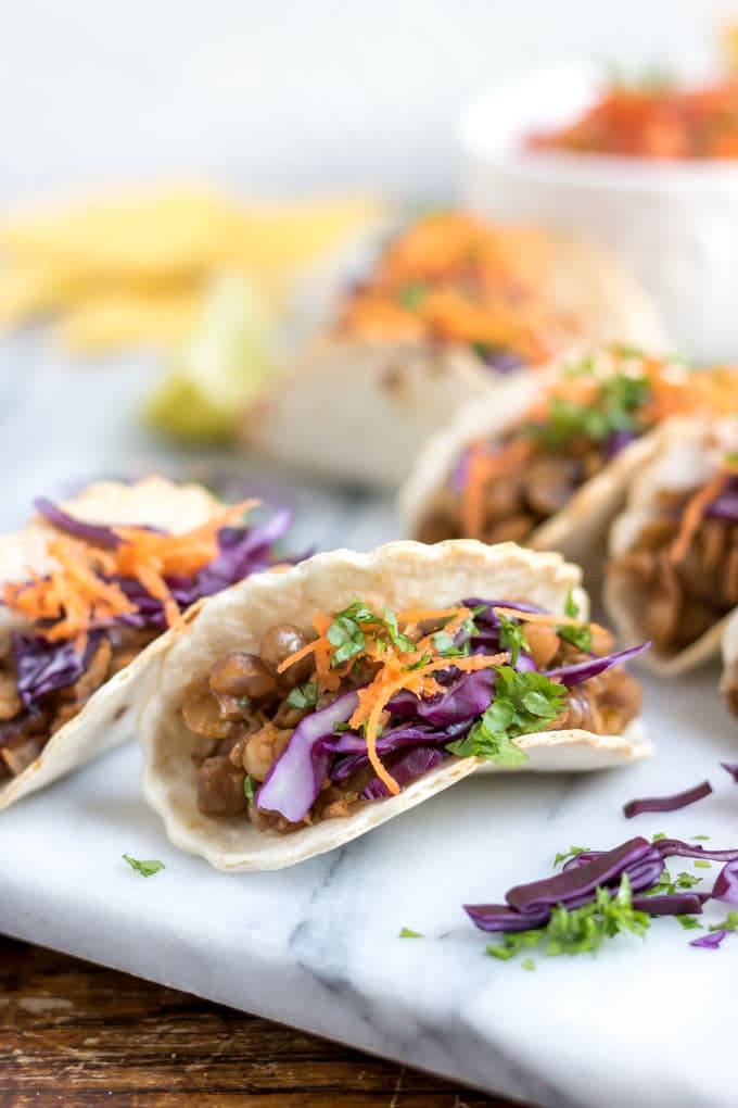 Close up of a mini taco with little taco shells, lentil taco meat and shredded veg.