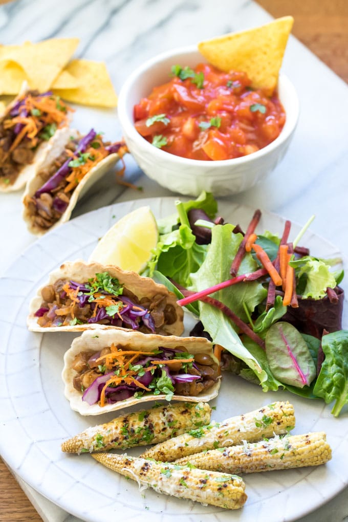 A plate of taco bites with baby Mexican corn on the side.