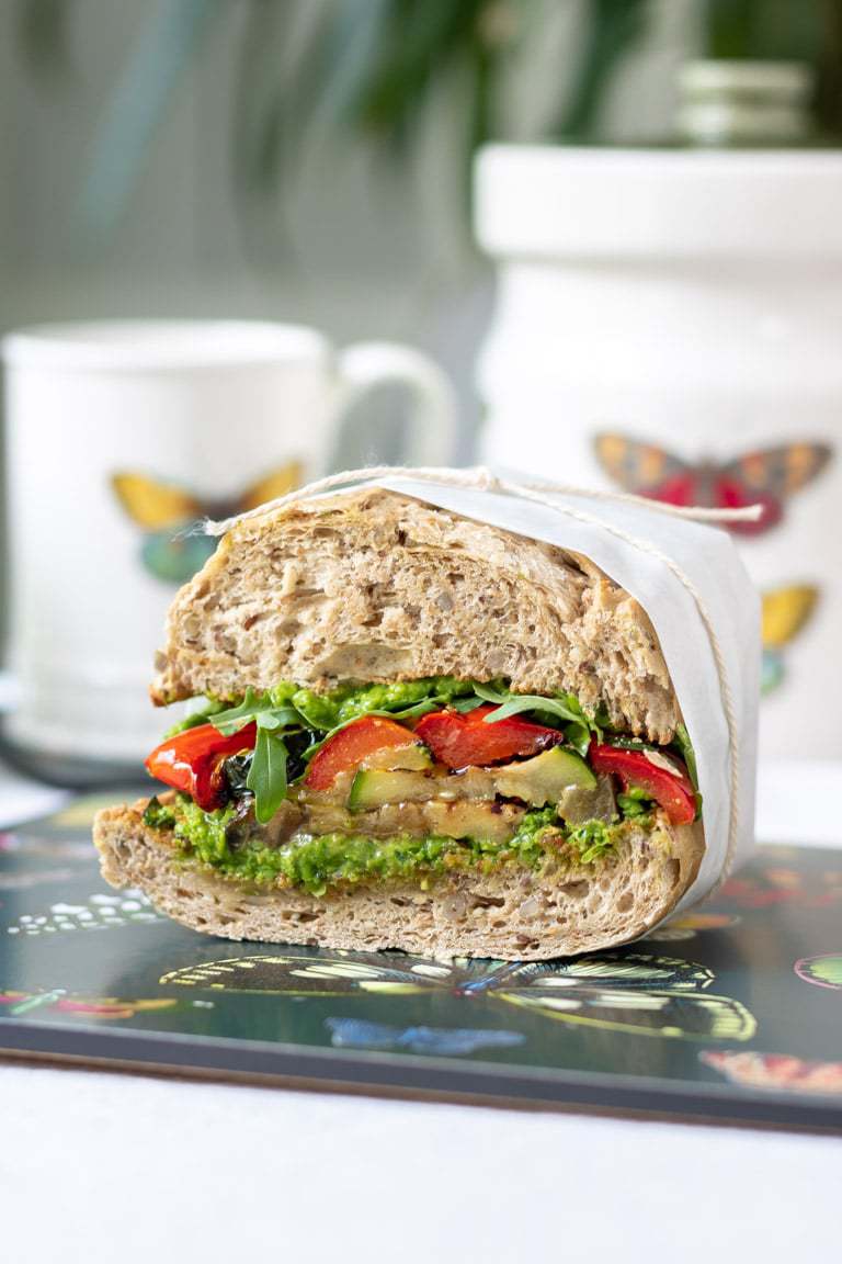 Close up of a roasted vegetable sandwich wrapped in paper and tied with string.