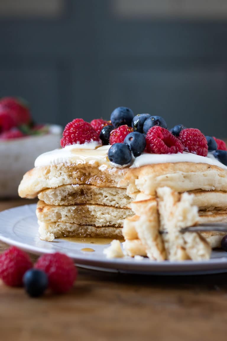 A stack of fluffy vegan pancakes with a bite out.