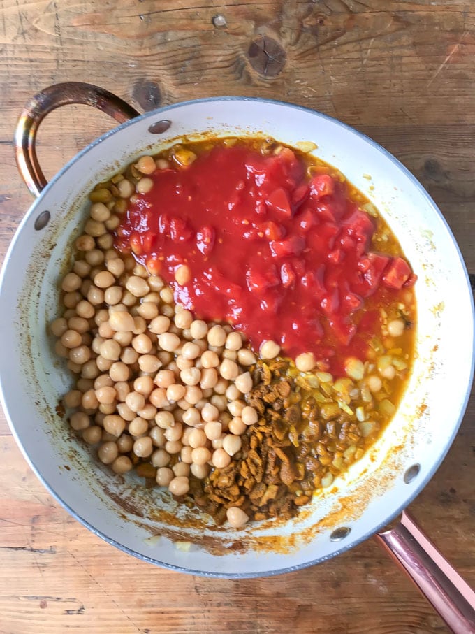 Pan of onions, spices, chickpeas and canned tomatoes.
