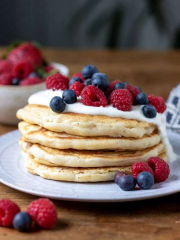 A stack of fluffy dairy free pancakes (vegan, eggless) vegan yogurt and fresh berries.