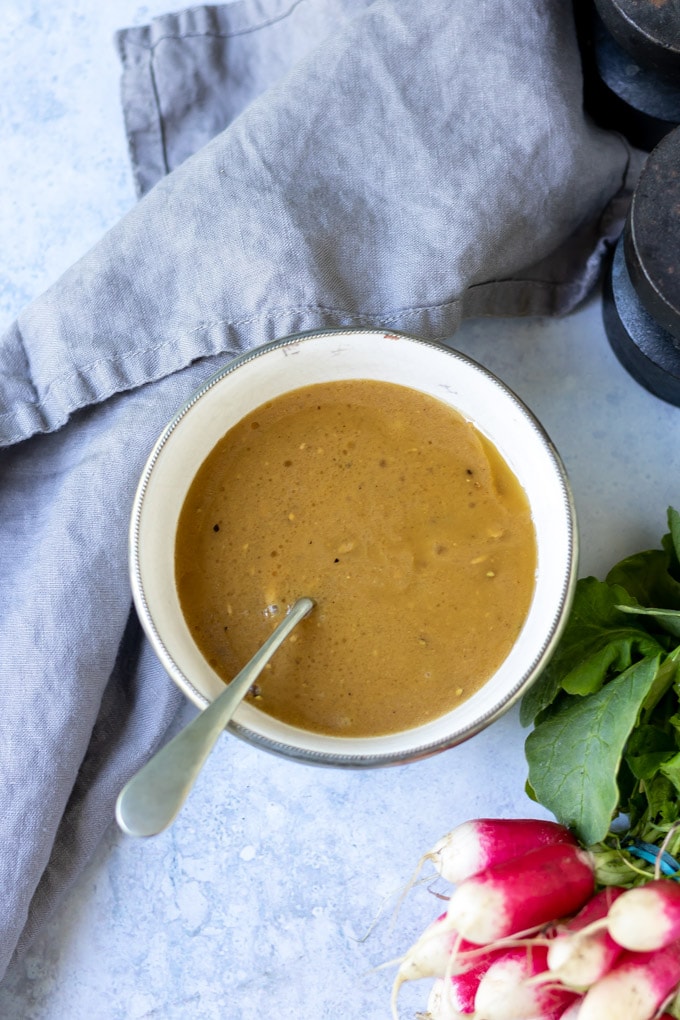 A bowl of easy tasty maple mustard dressing with dijon next to fresh radishes