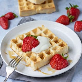 Table with a plate of waffles and strawberries.