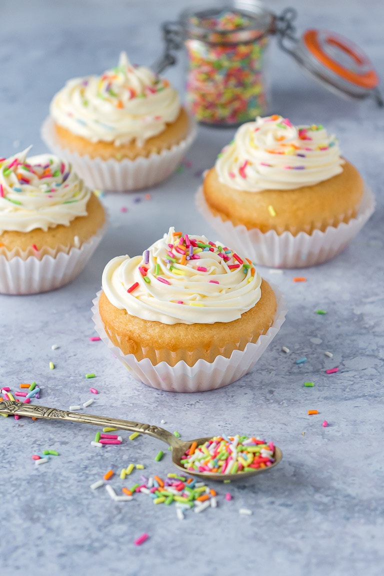 Four vegan cupcakes with frosting and sprinkles.