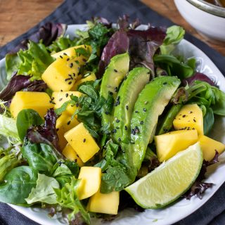 Close up of mango salad recipe, with lettuce, avocado, lime ginger dressing.