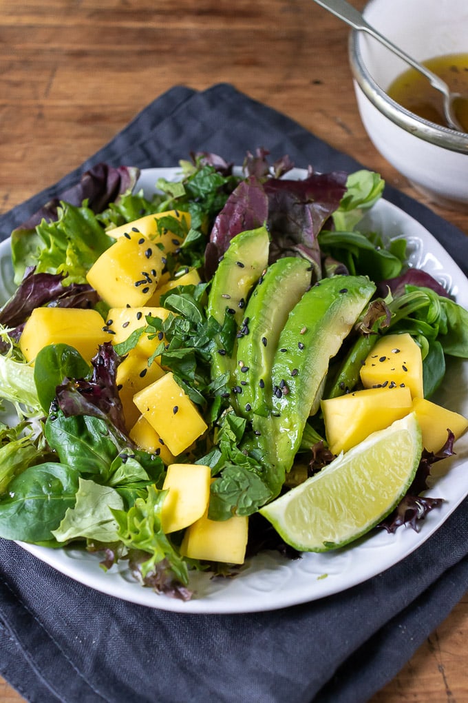 Close up of mango salad recipe, with lettuce, avocado, lime ginger dressing.