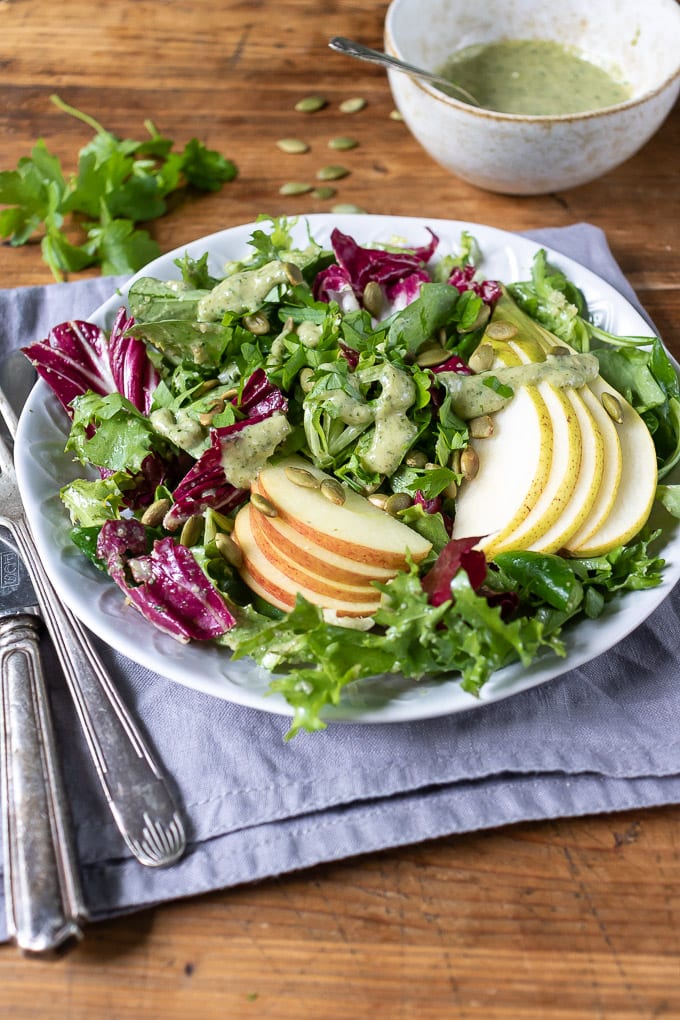 Overhead shot of a plate of green salad with slices of apple and pear