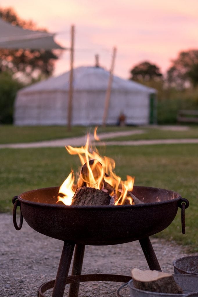 Fire pit ablaze with a yurt in the background.