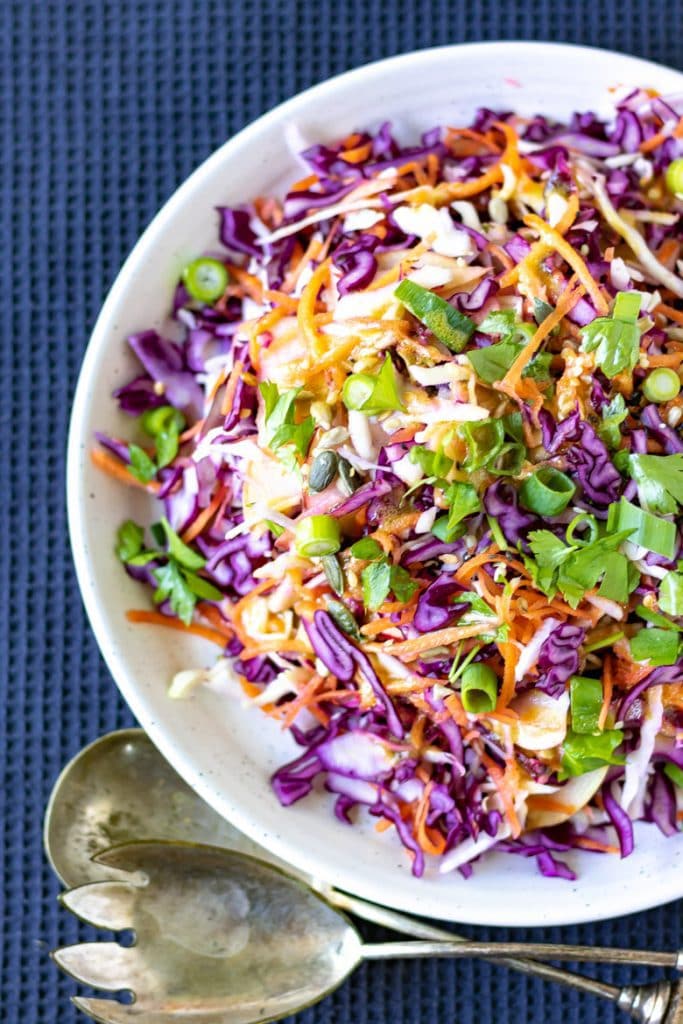 A serving plate piled with crunchy cabbage salad, a vinegar coleslaw with no mayo.