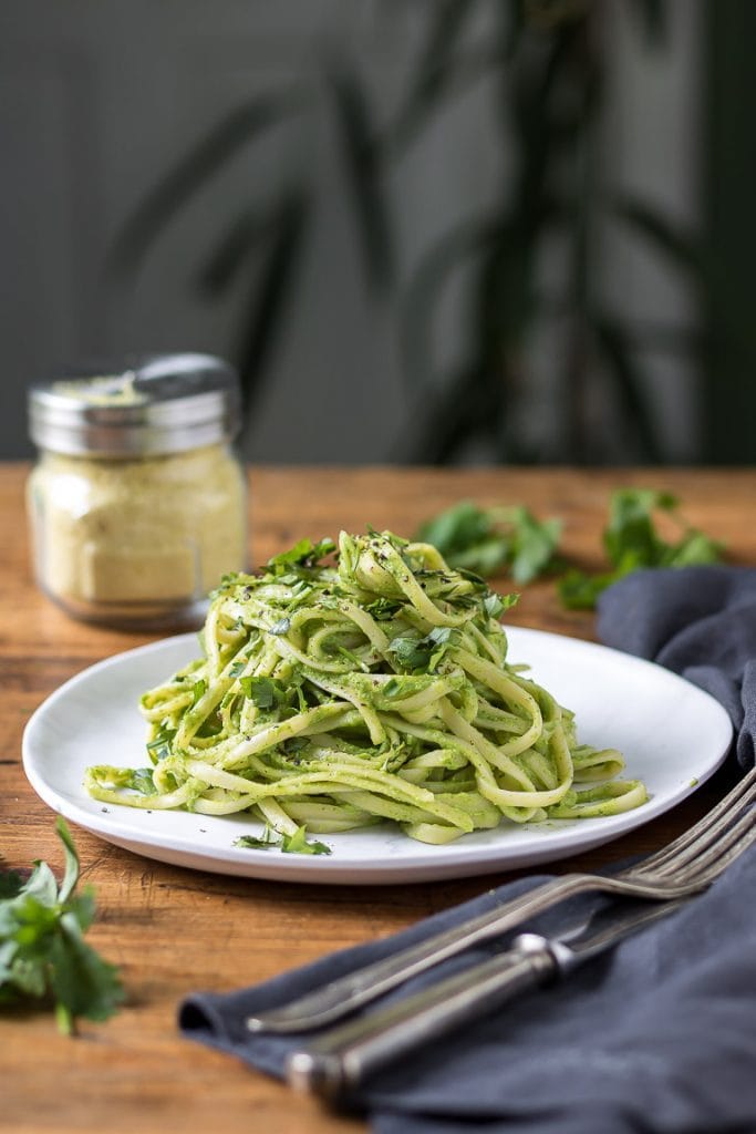 A plate piled with green spaghetti - pasta and a sauce made of avocado and herbs