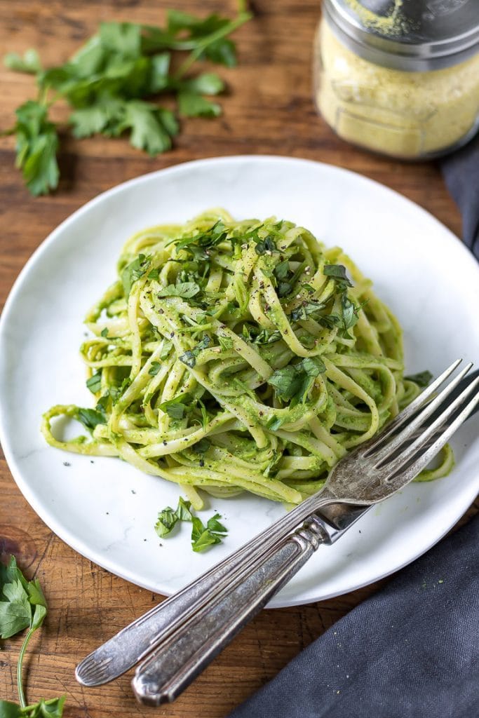 A white plate with green pasta - spaghetti with avocado sauce