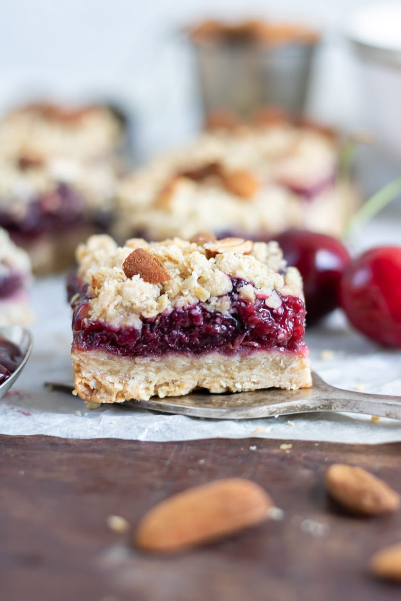 Close up of a cherry pie bar, with crumble topping.