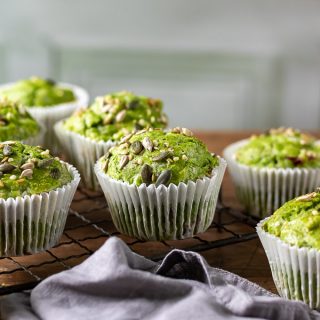 A wooden table with Kale Green Muffins recipe and grey napkin
