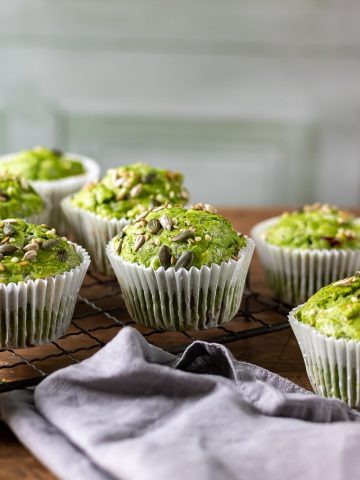A wooden table with Kale Green Muffins recipe and grey napkin