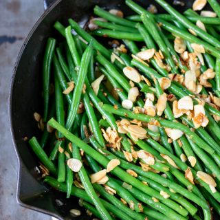A cast iron skillet with green bean almondine recipe - string beans with toasted almonds