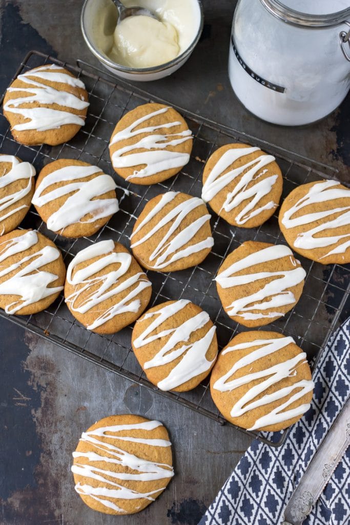 Overhead shot of soft iced pumpkin cookies with vanilla frosting drizzled on them.