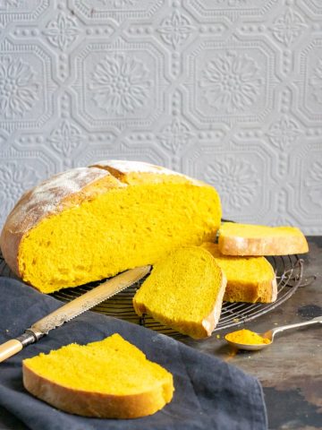 A loaf of Turmeric Bread recipe with slices cut next to it