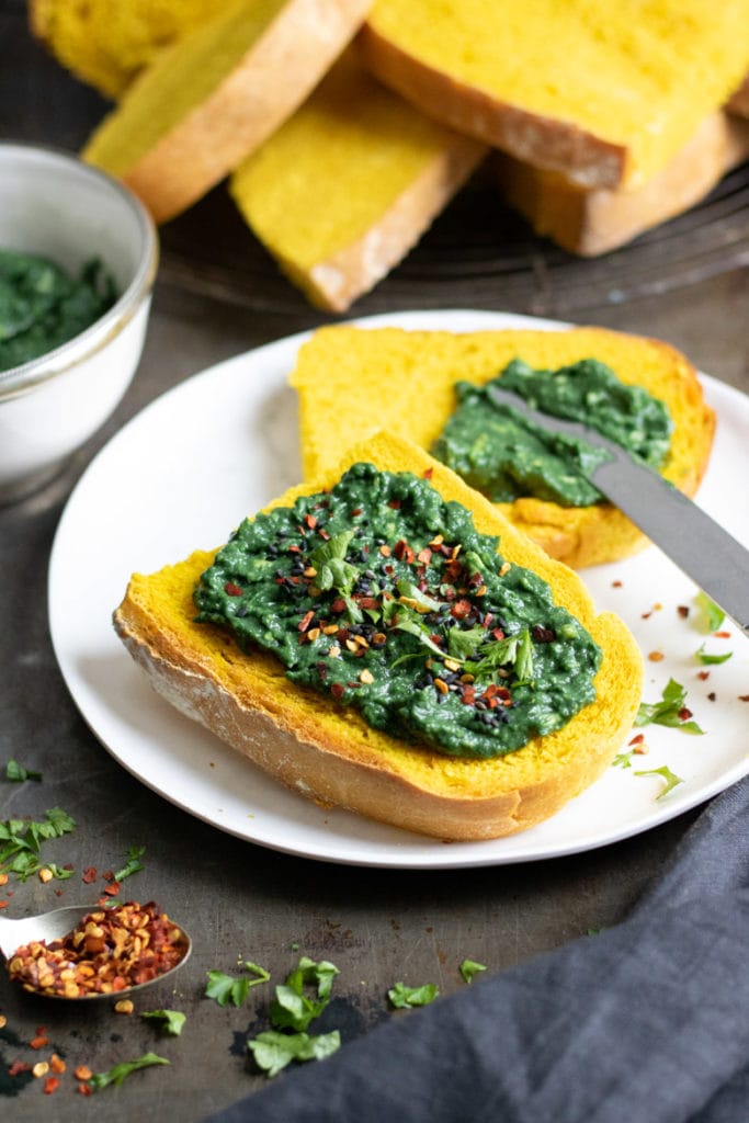 Slices of toasted Turmeric Bread with spirulina mashed avocado on it.