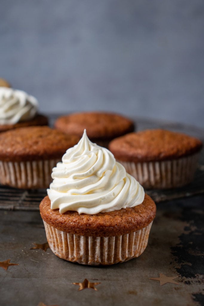 Close up of a gingerbread pumpkin cupcake with vanilla frosting.