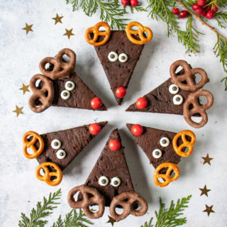 Reindeer brownies in a circle with red noses in the middle. Decorated for christmas with candy eyes and pretzel antlers.