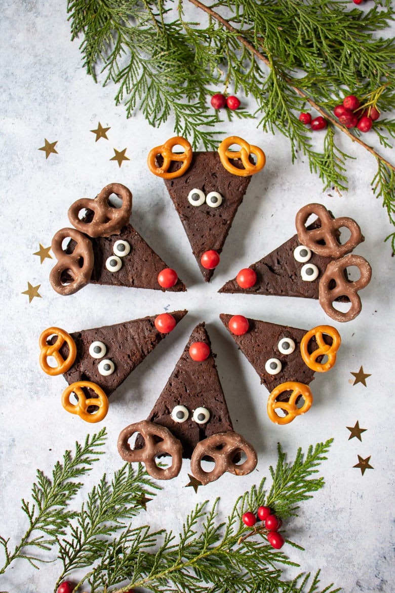 Reindeer brownies in a circle with red noses in the middle. Decorated for christmas with candy eyes and pretzel antlers.
