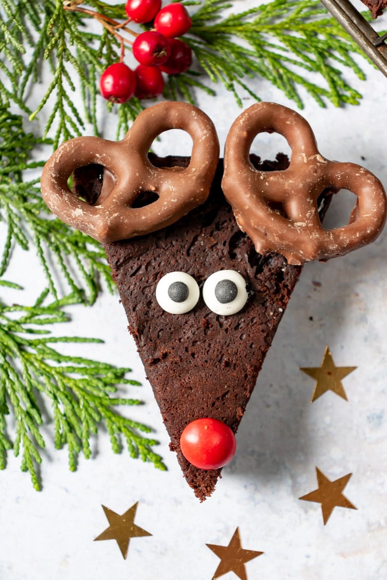 Close up of an avocado Reindeer Brownie recipe, with candy eyes, red candy nose and chocolate covered pretzel antlers.