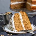A slice of vegan pumpkin cake with ginger frosting on a plate.