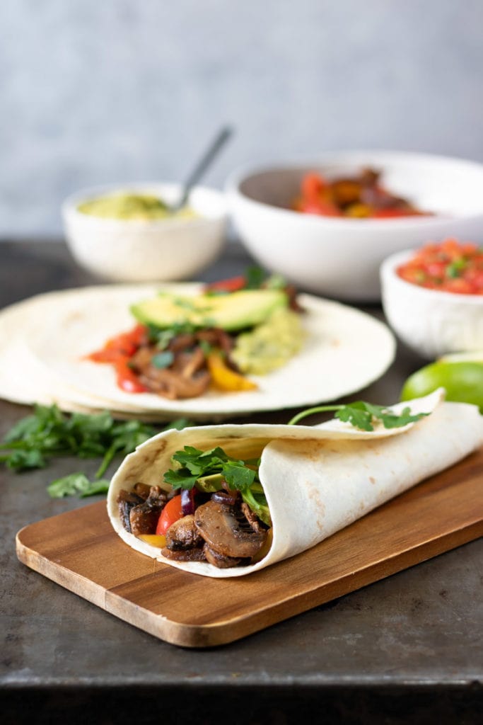 Meat free fajitas with mushrooms and vegetables on a wooden board