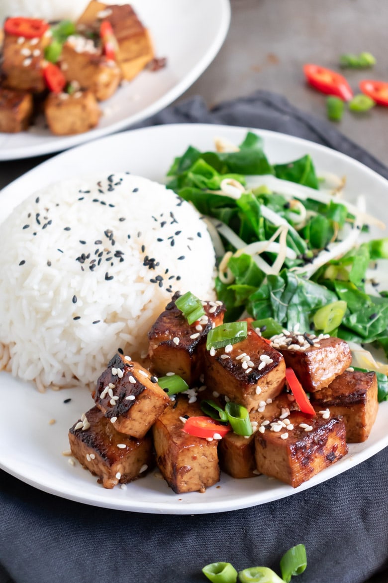 A plate with rice, stir fried greens and Asian tofu with Chinese marinade.