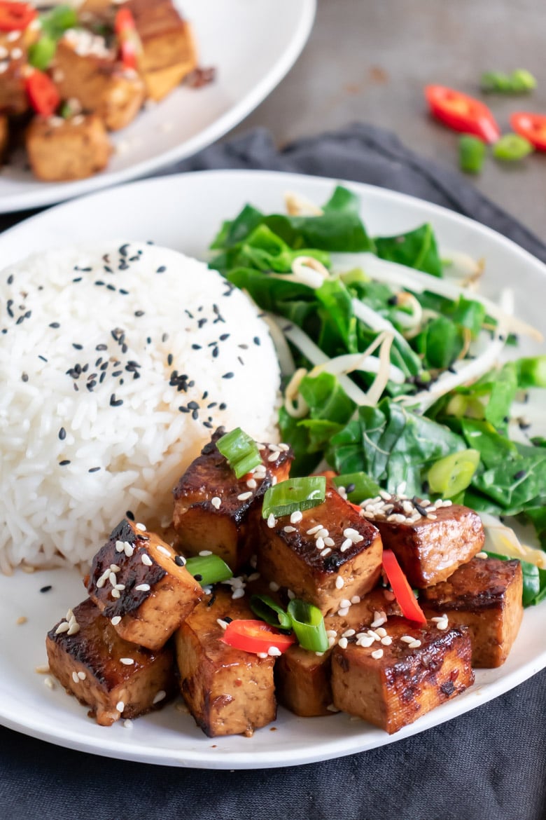 Close up of a plate of Chinese tofu, rice and greens recipe.