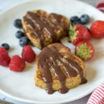 Close up of a plate with heart-shaped french toast, drizzled with chocolate yogurt sauce and berries