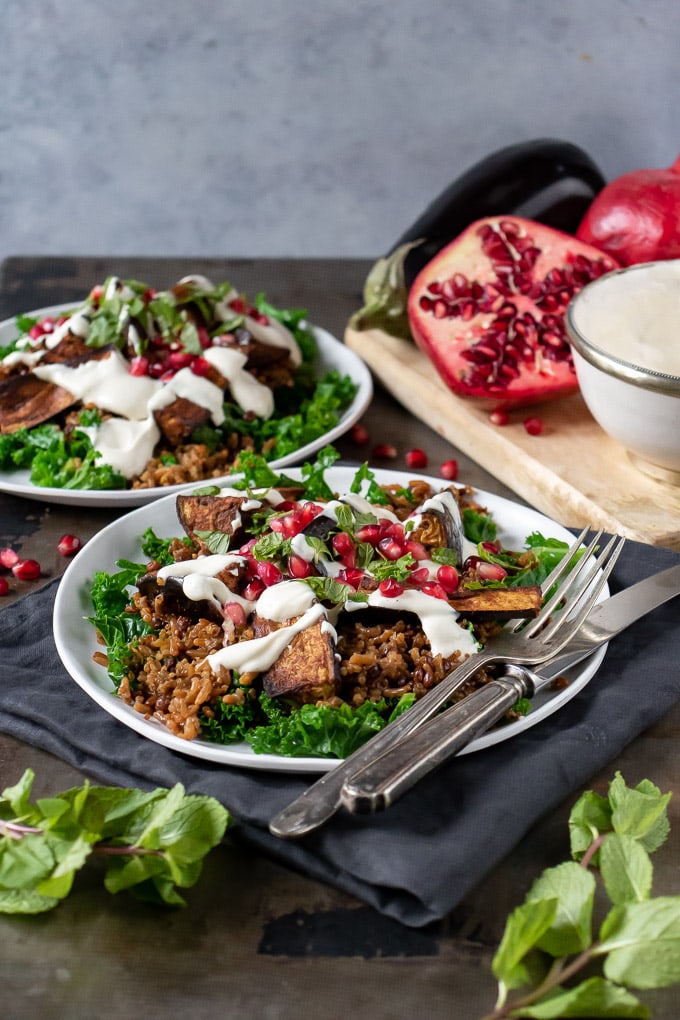 Plates with Persian Salad topped with Baked Aubergines and Tahini Dressing