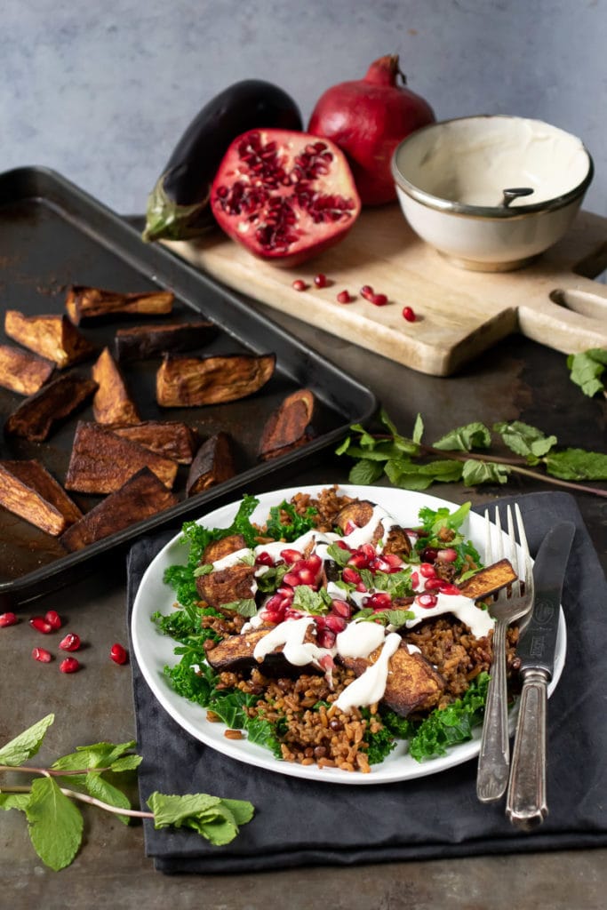 Persian Roasted Eggplant Salad with tahini dressing, next to a tray of baked aubergine.