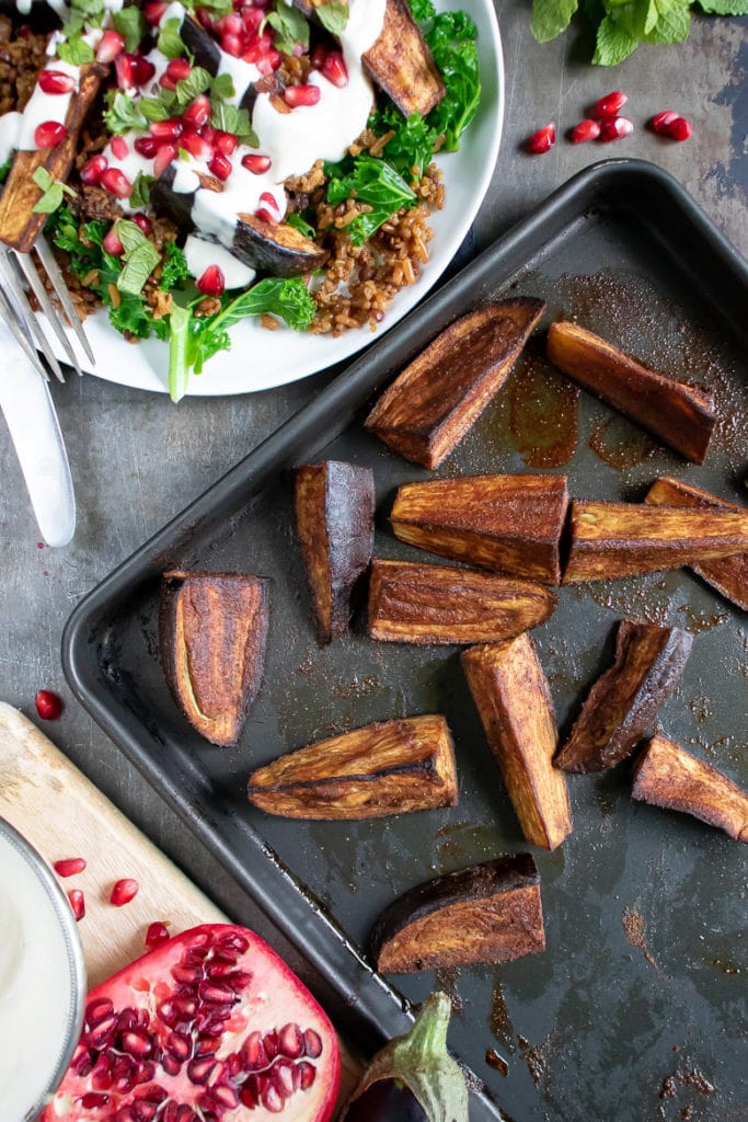 A tray of roasted eggplant wedges next to a persian salad