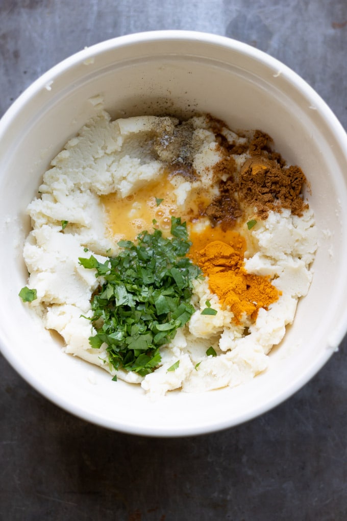 a bowl of mashed potato, spices and herbs.