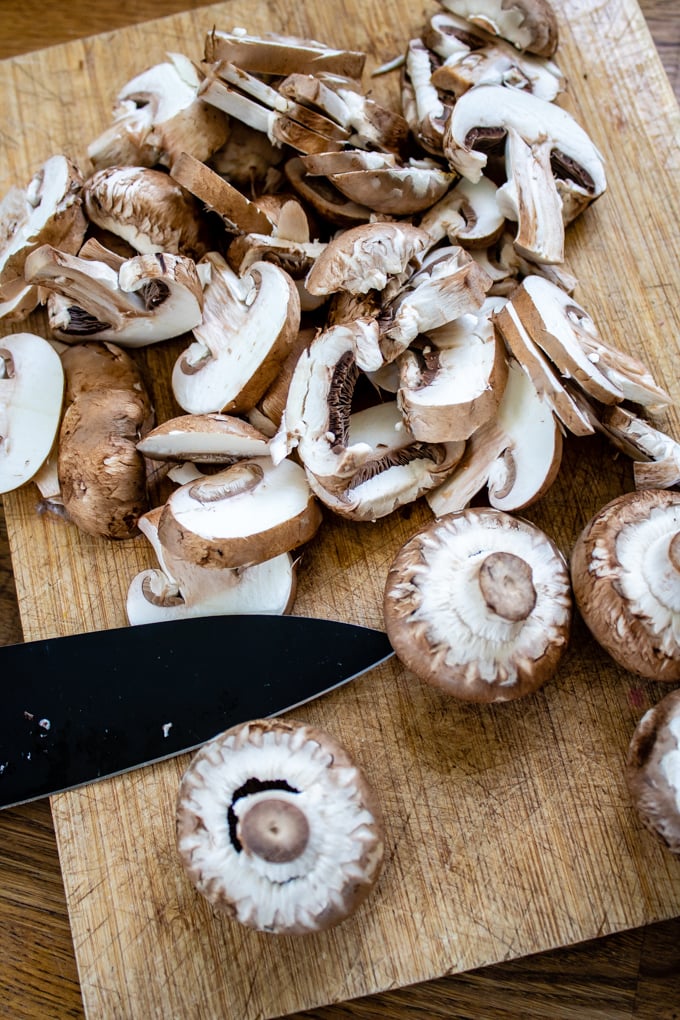 A wooden cutting board with chopped mushrooms.