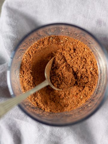 Jar of baharat spice with a spoon.